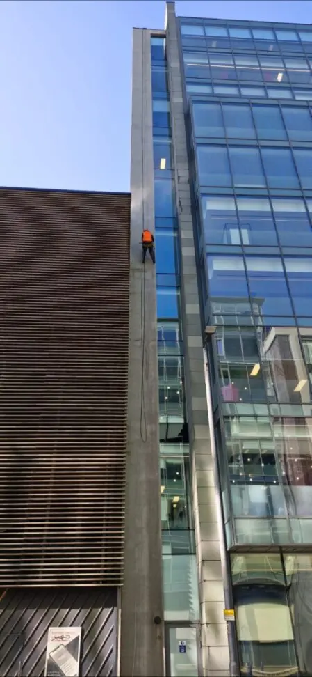 Rope access technicians installing signage on a building