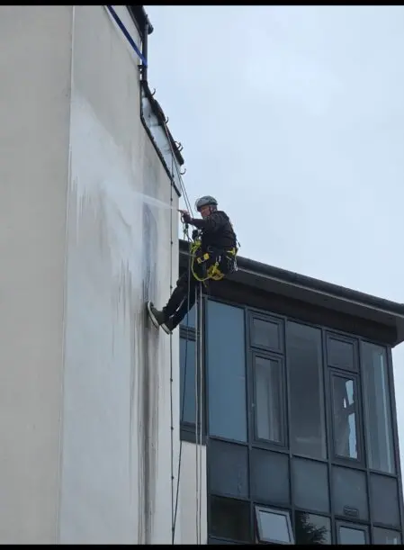 Rope access worker cleaning a building facade at height