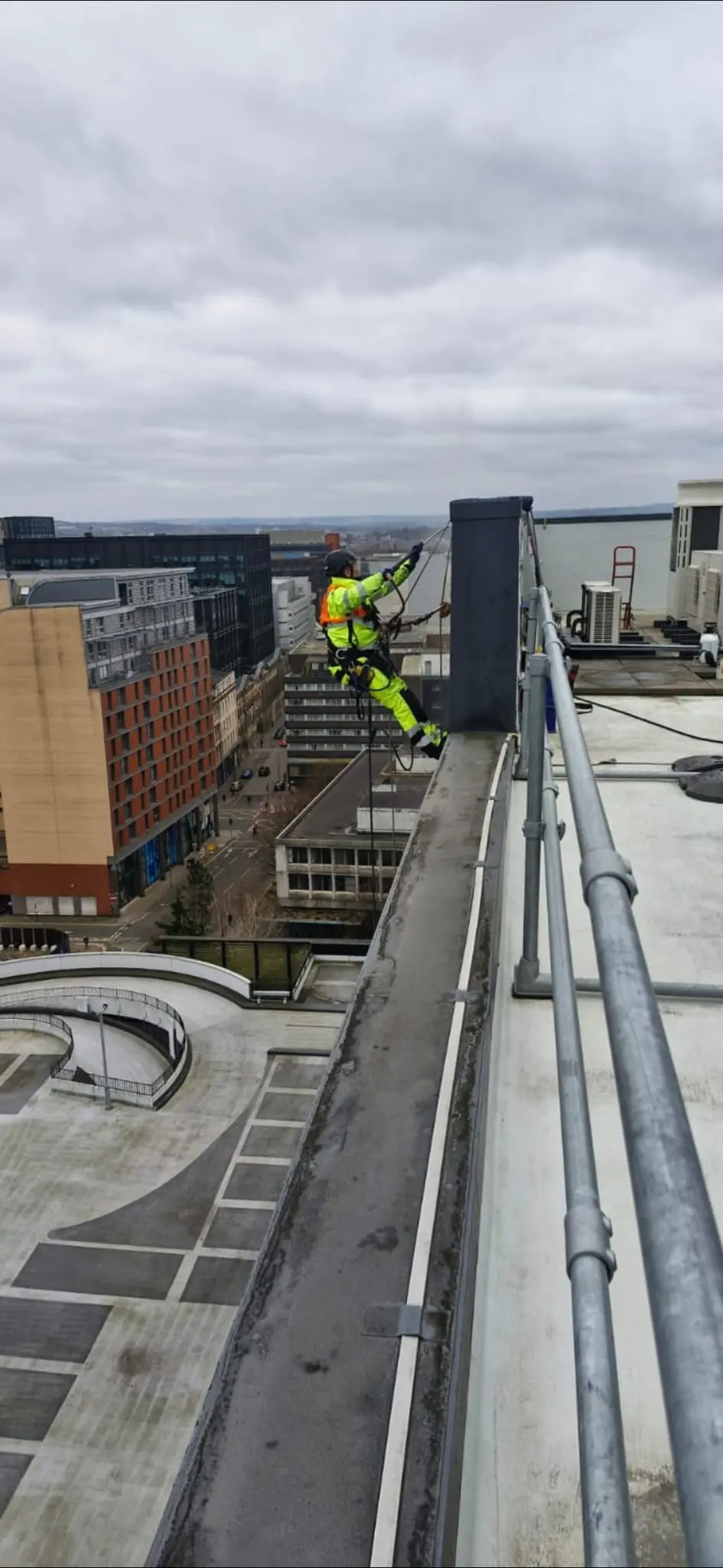 Technician cleaning a building facade using rope access