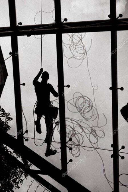 Rope access technician cleaning high-rise windows